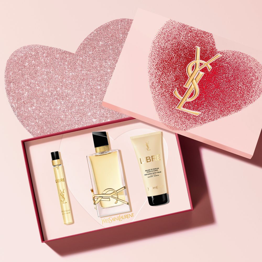 Coffret de presente para o Dia dos Namorados com o perfume Libre Eau de Parfum, contendo frascos de 90ml, 10ml e um balsamo corporal perfumado, em uma caixa rosa com coracoes brilhantes.